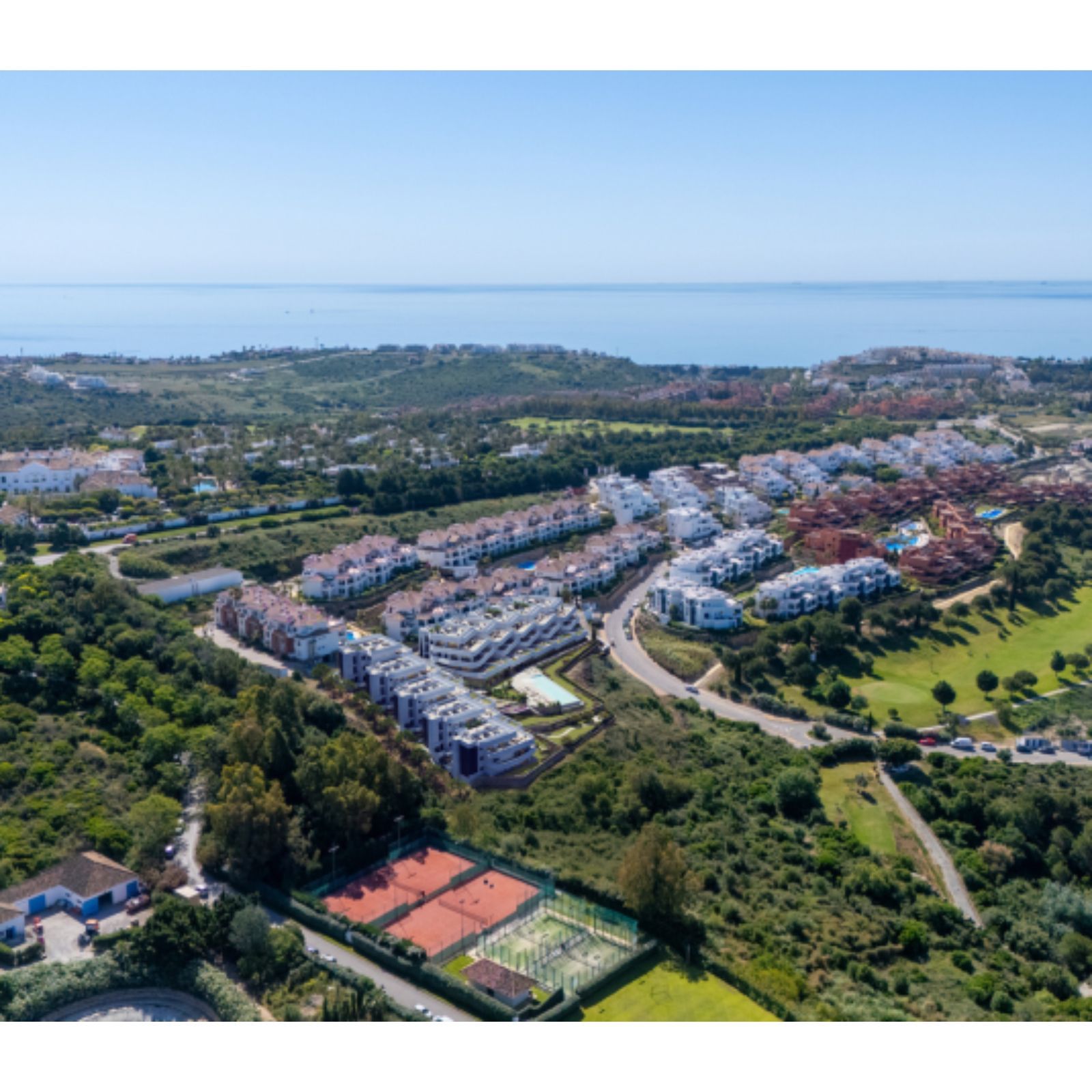 Luchtfoto van onroerend goed Skye Casares met tennisbanen, golfbaan en zeezicht.
