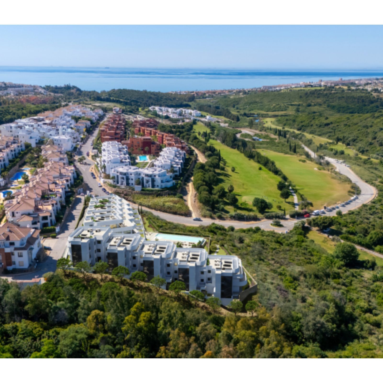 Luchtfoto van Skye Casares appartementencomplex met uitzicht op zee en golfbaan.